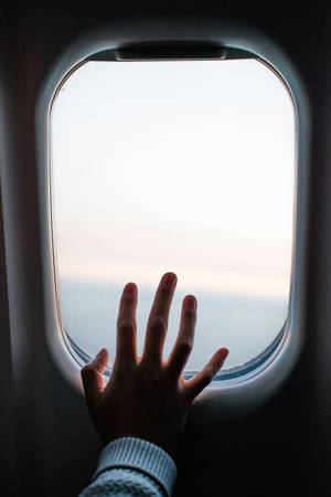 日出或日落時觸摸飛機窗戶的手 — 旅行 壁紙