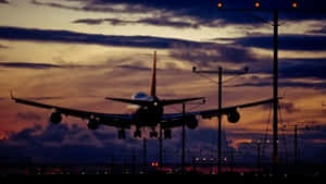 飛機在黃昏時分降落，天空色彩繽紛，跑道燈光亮起。 — 黃昏 壁紙