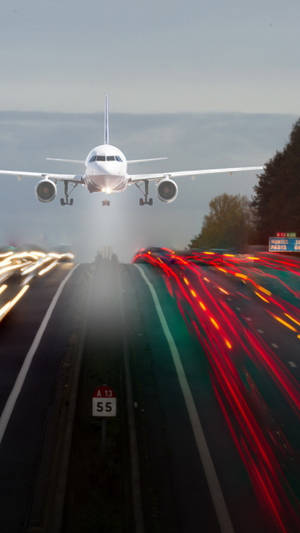 飛機接近高速公路，模糊的汽車燈光在夜間下方形成條紋。