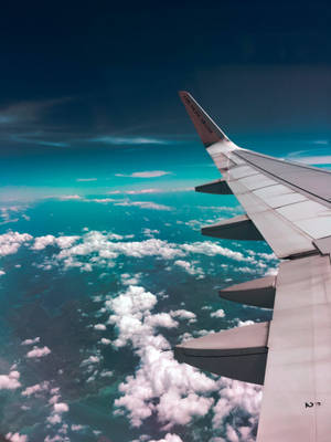 飛機機翼飛越海洋雲層和藍天。 — 深綠色 壁紙