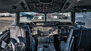 飛機駕駛艙內部，顯示控制裝置和座椅，外面可見機場。