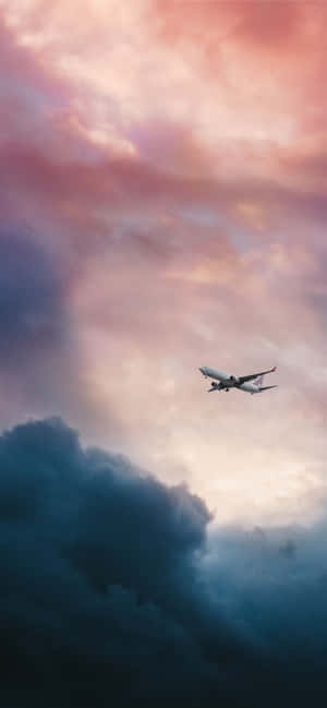 一架飛機飛過色彩繽紛的暮色雲層。 — ZTE Axon 壁紙