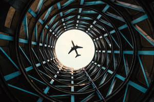 飛機在日落時分飛過圓形建築結構 — 天空景觀 壁紙