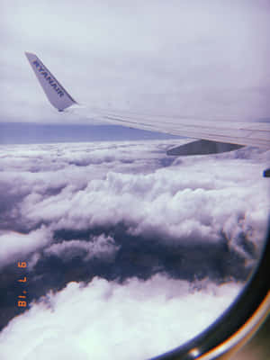 瑞安航空的機翼在雲層上方，從乘客窗戶看到，帶有菲林顆粒效果。