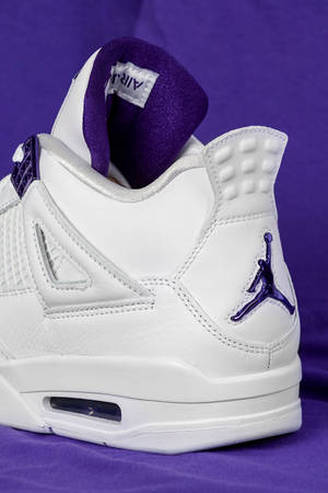 白色Jordan 4運動鞋，紫色細節，紫色背景。