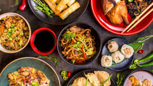 亞洲菜餚的盤子，包括餃子、麵條和春卷，排列在深色木桌上。