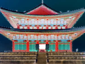 夜間被照亮的傳統韓國宮殿，帶有紅色和藍綠色細節。