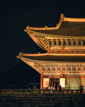 夜間點亮的傳統韓國宮殿，遊客在石徑上。