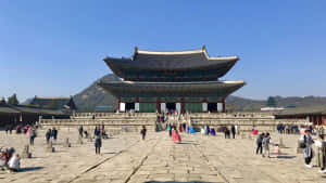 遊客探索一座歷史悠久的韓國宮殿，擁有傳統建築和石頭庭院。