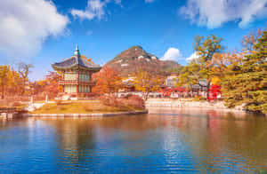 湖邊的韓國亭子，周圍環繞著秋樹和一座山。