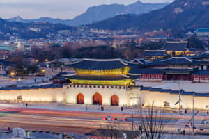 黃昏時分照明韓國宮殿大門，下方有城市燈光和車流線條。