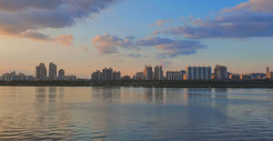 夕陽下的城市天際線倒映在平靜的河水之中。