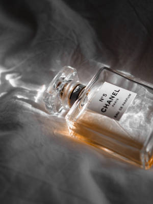 Chanel No 5 香水瓶放在有紋理的灰色布料上，光線柔和。