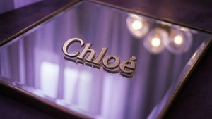 鏡面上的金色 Chloe 標誌，柔和紫色燈光，背後模糊燈光。