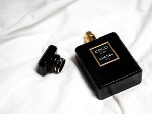 黑色 Chanel Coco Noir 香水瓶，金色瓶蓋，置於白色布料上。