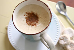 肉桂粉 latte 在陶瓷杯中，旁邊有曲奇和匙羹。