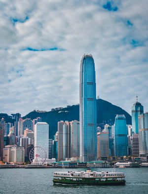 渡輪在多雲的天空下駛過香港標誌性的摩天大樓和山脈。 — 2048x2732 壁紙