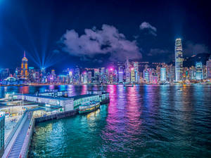 香港夜晚的天際線，色彩繽紛的燈光倒映在水面上。