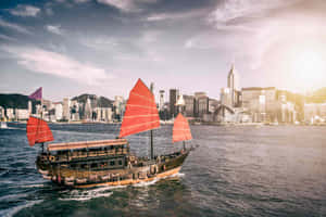 傳統中式帆船在日落時分駛過香港現代化的天際線。 — 天際線 壁紙