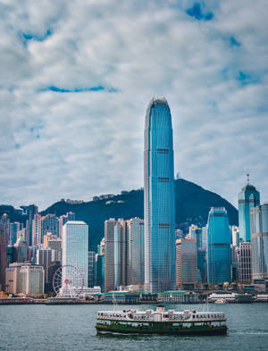 渡輪在多雲的天空下駛過香港標誌性的摩天大樓。