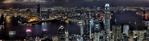 夜晚的香港城市景觀，燈火通明的摩天大樓和海港船隻。 — 3840x1080 GIF 壁紙