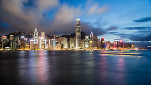 香港天際線在黃昏時分，城市燈光倒映在水面上。