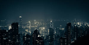 夜間城市景觀，有燈火通明的摩天大樓和黑暗的天空。