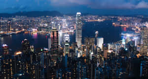 夜間香港天際線，燈火通明的摩天大樓和港口燈光。 — 香港 壁紙