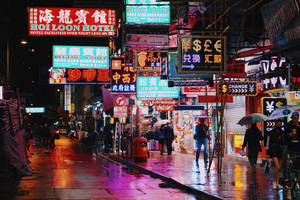 夜雨中的繁華霓虹城市街道，行人撐傘。