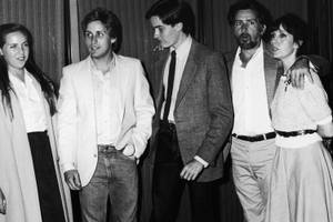 五個穿著1980年代服裝的人在室內窗簾旁擺姿勢。