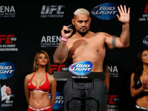 UFC拳手喺稱重活動中，旁邊有兩位著比堅尼嘅擂台女郎。