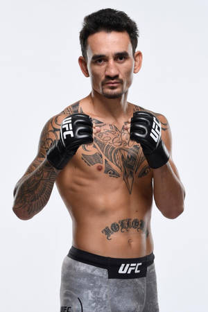 一位有紋身的男性UFC拳手，戴著手套和灰色短褲，擺出戰鬥姿勢。