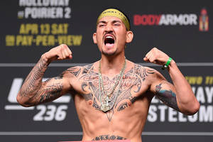 有紋身的MMA拳手在稱重活動中舉起拳頭咆哮。