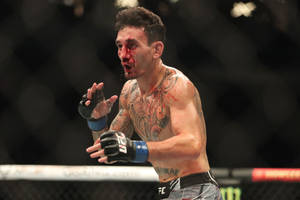 一名滿臉鮮血、帶有紋身的勝利MMA拳手在八角籠內慶祝。