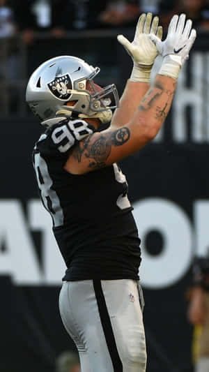 穿著Raiders球衣的足球員舉臂慶祝。