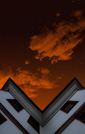 白色建築屋頂襯著火橙色星空和雲彩。 — Galaxy Tab S10+ 壁紙