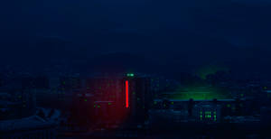 夜間城市，紅色和綠色的建築燈光在黑暗的山脈背景下閃耀。 — 時鐘 壁紙