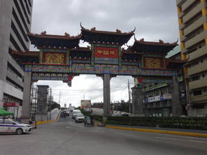 城市中的中式牌坊，有交通和建築物 — 唐人街 GIF 壁紙