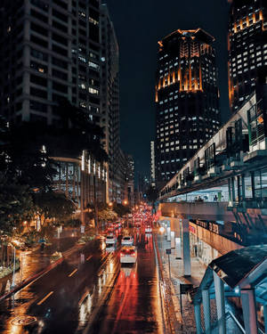 夜晚城市街道，濕漉漉的路面反射著車燈和高樓大廈。 — 夜景城市 壁紙