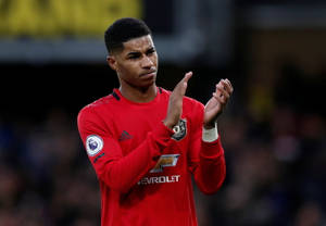 身穿紅色曼聯球衣的足球員在夜間比賽中拍手。