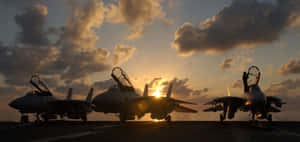 三架戰鬥機在日落時分於航空母艦上，伴隨戲劇性的雲彩。