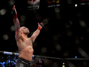 MMA拳手在八角籠中舉臂慶祝勝利。