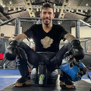 MMA戰士微笑著坐在籠內，配備訓練裝備。 — 拳擊 壁紙
