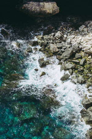 從空中俯瞰，綠松石色的海浪拍打著灰色岩石。 — 海浪 壁紙