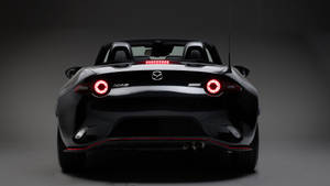黑色Mazda MX-5 Miata開篷跑車後視圖，在攝影棚中帶有發光的紅色尾燈。