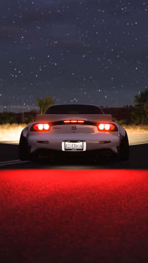 白色跑車配紅色尾燈，在星光燦爛的夜空下駛於發紅光的道路。