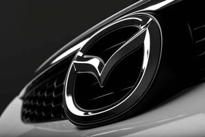 黑色汽車格柵上帶有金屬光澤的閃亮Mazda標誌。