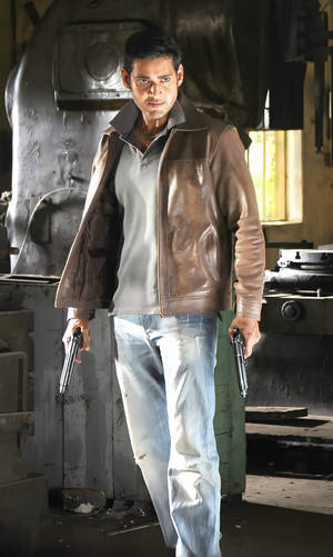 身穿皮褸的男子在金屬工廠中手持兩把手槍。