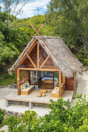 木製海灘小屋，茅草屋頂，戶外座位，周圍綠意盎然。 — 彈丸論破 壁紙
