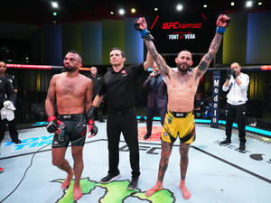 UFC拳手在八角籠中獲勝，裁判舉起他的手。